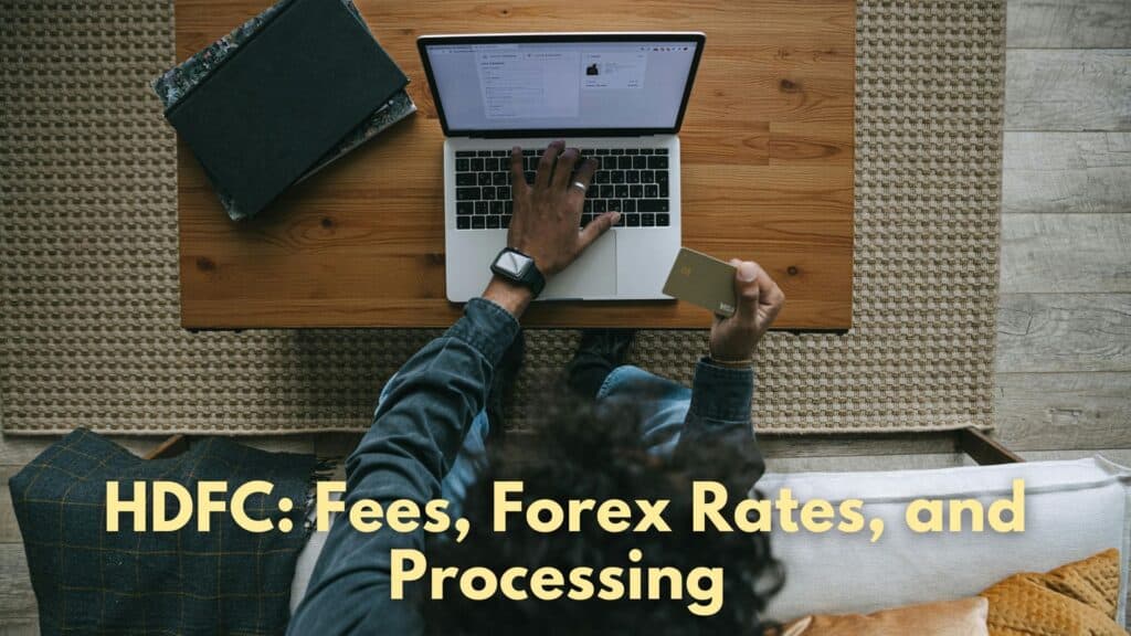 Man sending money abroad online in his laptop by referring to his card details. Text added below features "HDFC: Fees, Forex Rates, and Processing.
